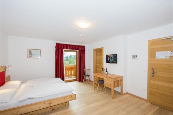 Hotelová izba s manželskou posteľou, pracovným stolom a francúzskym oknom na balkón.