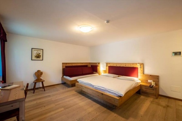 Hotelová izba s manželskou posteľou, pohovkou a dreveným nábytkom.