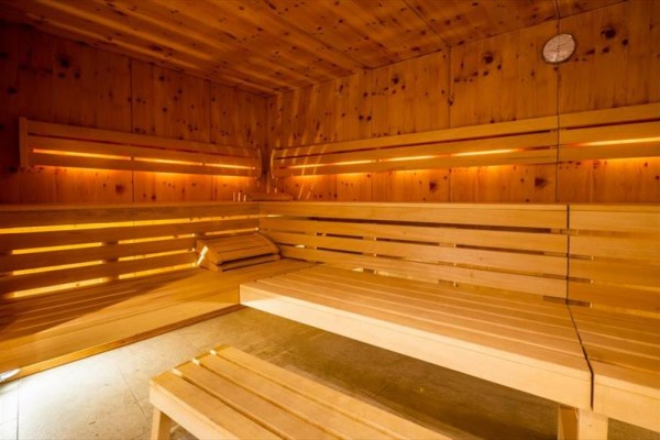 Interiér drevenej sauny s lavičkami a jemným osvetlením.  