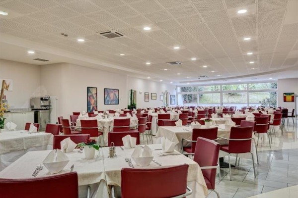 Jedáleň s červenými stoličkami a bielymi obrusmi, pripravená na hostí.