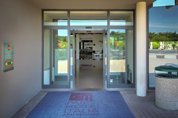 Vstup do hotela s automatickými dverami a rohožkou s logom.