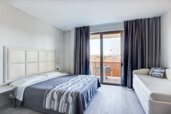 Moderná spálňa s manželskou posteľou a balkónom.