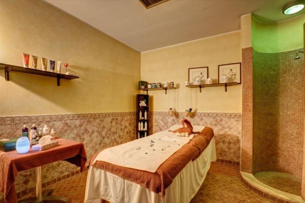 Masážna miestnosť s masážnym stolom a policami s kozmetikou.