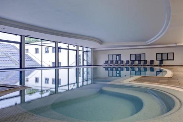 Krytý bazén s vírivkou a radou prázdnych lehátok pri stene.