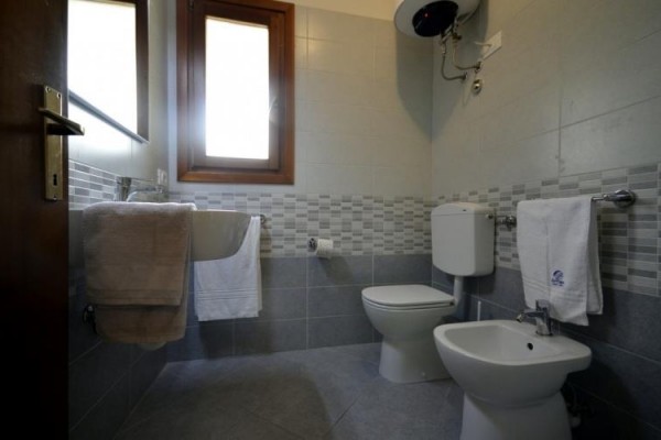 Kúpeľňa s umývadlom, toaletou, bidetom a uterákmi na vešiakoch.