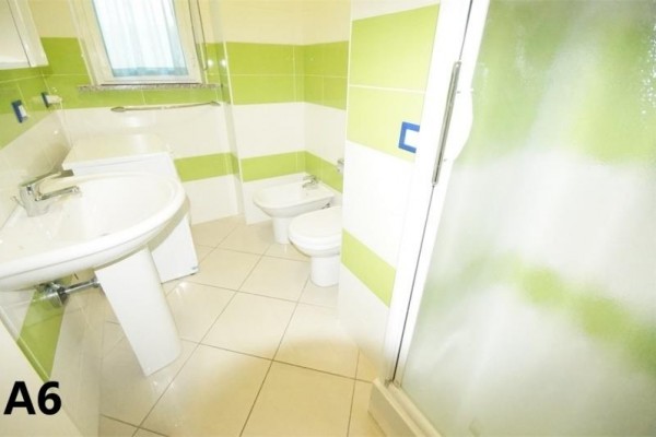 Kúpeľňa s umývadlom, bidetom, záchodom a sprchovým kútom s obkladmi v zelenej farbe.