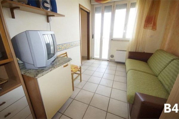 Malá izba s pohovkou, televízorom a balkónovými dverami.