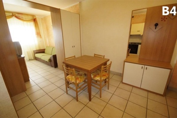 Obývacia izba s jedálenským stolom, stoličkami, pohovkou, televíziou a skriňou.