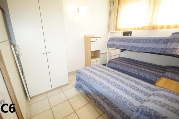 Izba s poschodovou posteľou, jednolôžkom, vstavanou skriňou a komodou.