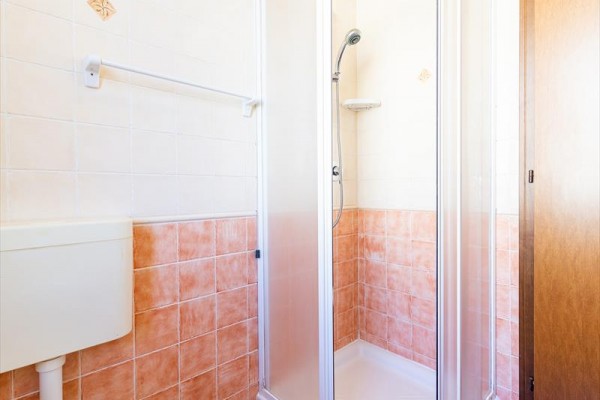 Sprchovací kút v kúpeľni s oranžovými a bielymi obkladačkami.