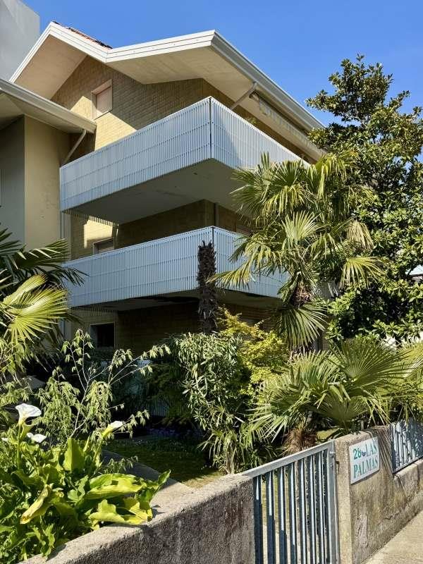 Moderný dom s veľkými balkónmi obklopený tropickou vegetáciou.