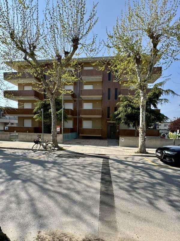 Budova s drevenými balkónmi obklopená stromami.