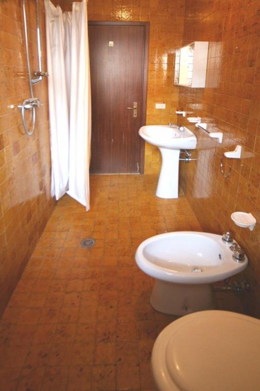 Kúpeľňa s hnedými obkladmi, sprchovacím kútom, umývadlom, bidetom a toaletou.