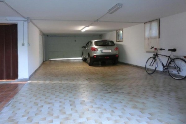 Zaparkované auto v garáži vedľa bicykla.