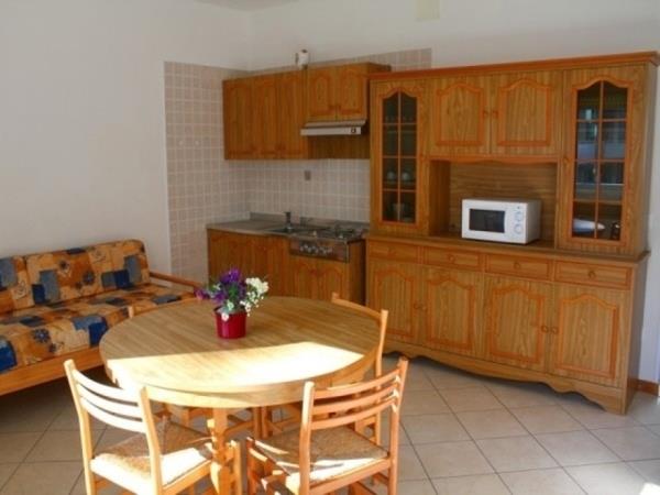 Kuchynský kút s dreveným nábytkom vrátane stola, stoličiek a gauča, s mikrovlnnou rúrou na skrini.