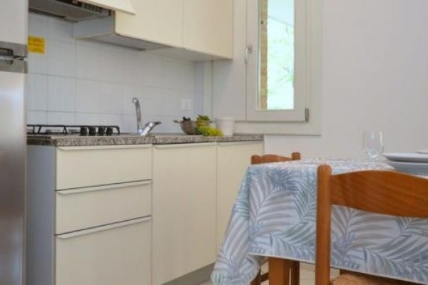 Kuchynský kút s jedálenským stolom a stoličkami, vedľa chladničky a sporáka.