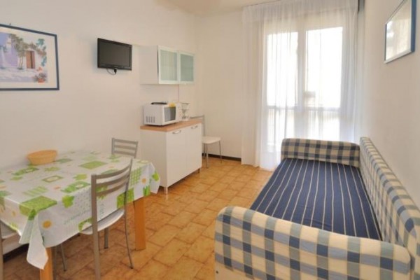 Malá obývacia izba s jedálenským stolom, pohovkou a kuchynským kútom.  