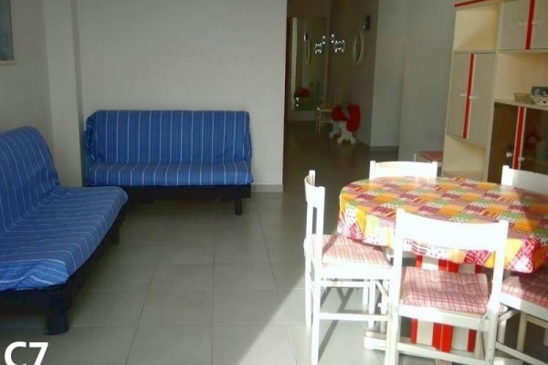 Obývacia izba s modrými gaučami a jedálenským stolom s kockovaným obrusom.