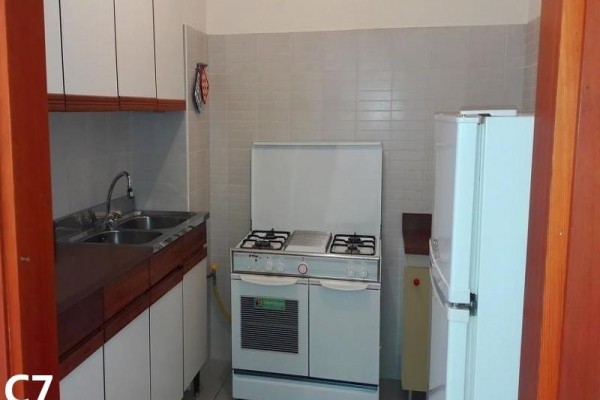 Malá kuchyňa s plynovým sporákom, drezom a chladničkou.  