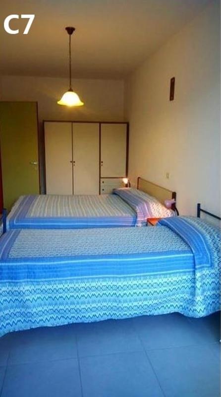 Dve jednolôžkové postele s modrou posteľnou bielizňou v izbe so šatníkovou skriňou.