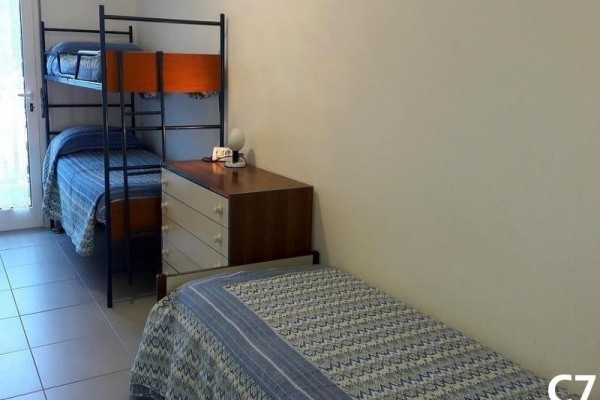 Izba s jednolôžkovou posteľou, poschodovou posteľou a komodou.