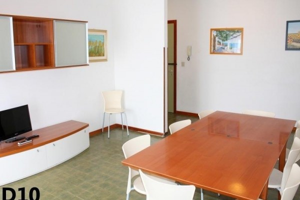 Obytný priestor s veľkým dreveným stolom, stoličkami a televízorom v rohu.