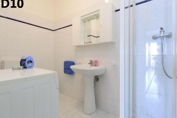 Kúpeľňa s umývadlom, sprchovacím kútom, zrkadlom a práčkou.