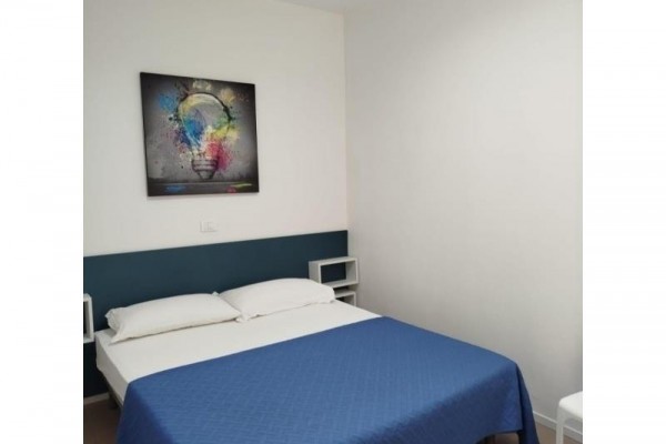 Otvorené dvere vedúce z izby na balkón s výhľadom na strom.